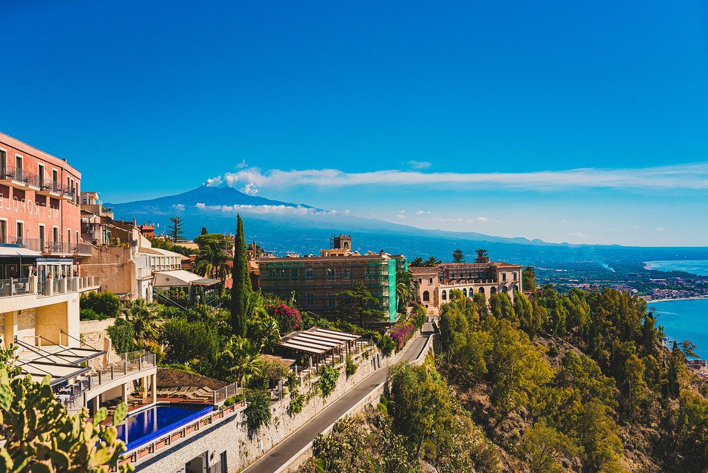 Sicily coastal town of Taormina with Mount Etna at sunset, cliffs, and Mediterranean architecture